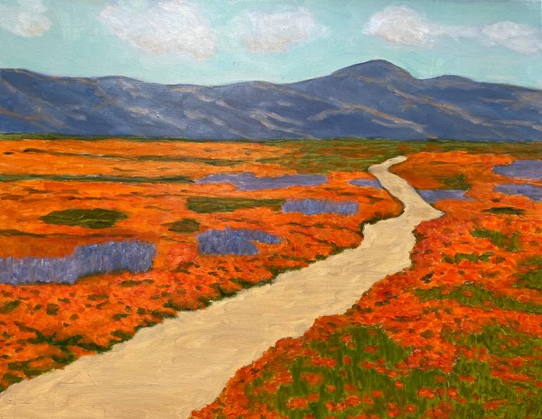 A wide shot of a field of California poppies and other wildflowers in bloom, with the Pacific Ocean visible in the background.