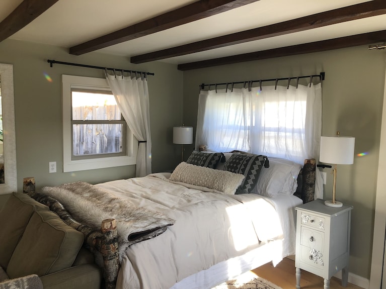 Image of a cozy bed layered with different types of linens: wool blanket, cotton sheets, down comforter.