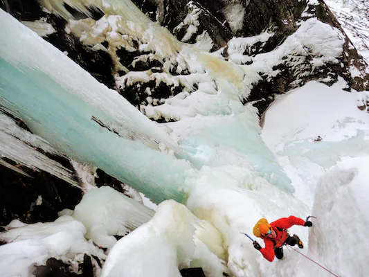 Ice climber ascending a frozen waterfall in Rjukan