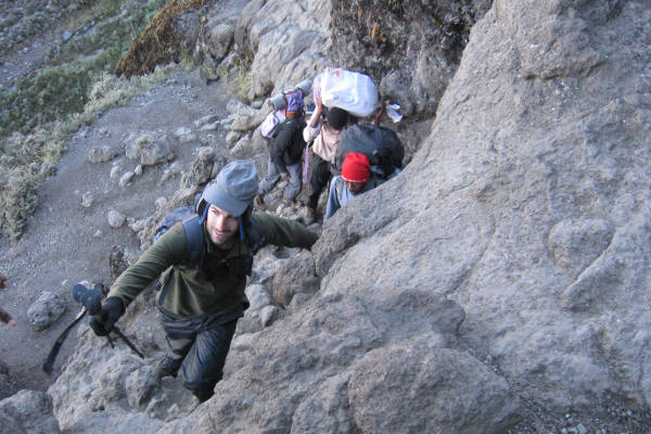 A climber dangling precariously from the 'Ponte Cristallo' suspension bridge of the Ivano Dibona Via Ferrata, showing the extreme drop below.
