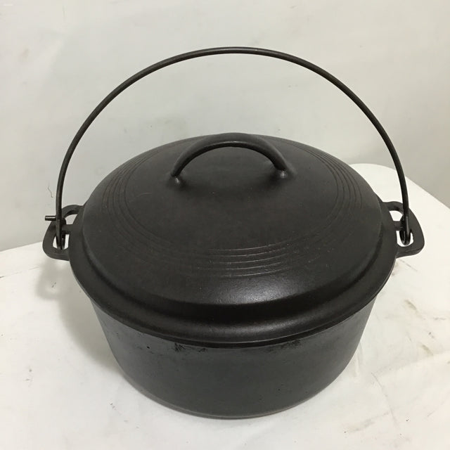 A hand holding a brown cloth inside a cast iron skillet, wiping oil around to maintain seasoning.