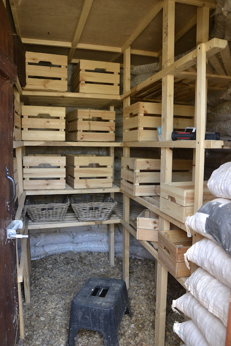 Shelves stacked with potatoes, onions, and other vegetables