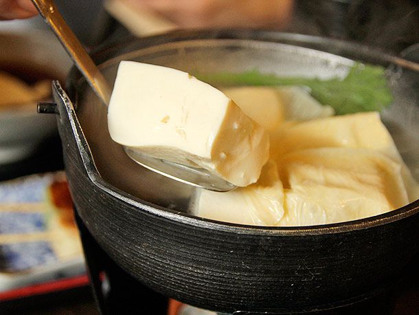 A bubbling pot of Yudofu at Okutan Nanzenji, with accompanying dipping sauces and condiments arranged beside it. The simplicity and elegance of the dish are evident.