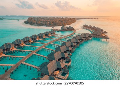 Aerial sunset landscape of a luxury tropical Maldives bungalow, showcasing the private deck and crystal clear waters.