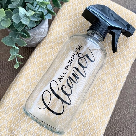 A rustic kitchen scene features homemade orange vinegar spray and cleaning supplies on a wooden countertop