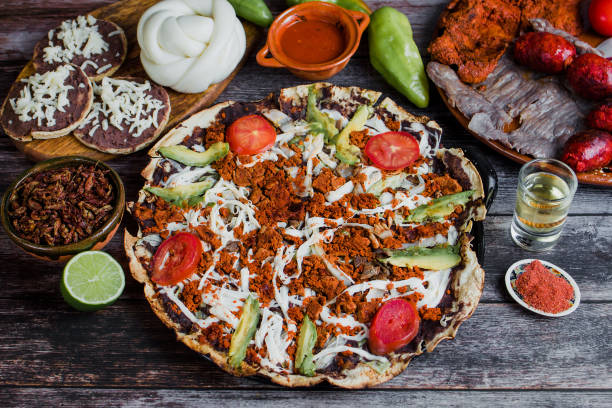 A close-up of a tlayuda, showcasing its large size, crispy texture, and variety of toppings