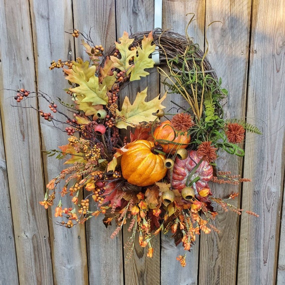 A vintage wooden crate styled with pumpkins, gourds, a cozy blanket, and string lights for a charming fall entryway display