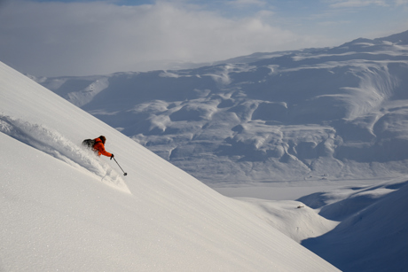 Heliskiing in the Troll Peninsula with Deplar Farm, capturing the vast landscape and the skier's movement through powder.