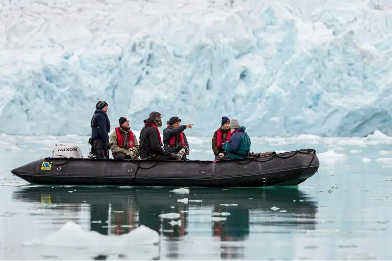 An Arctic landscape with a small ship cruising through icy waters, showcasing the beauty and remoteness of the region.
