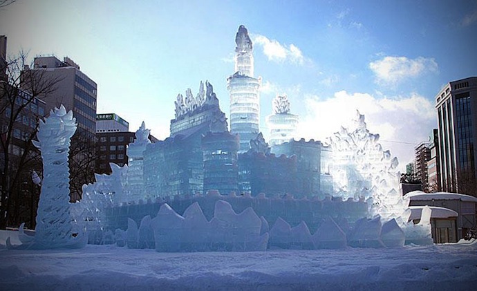 A wide-angle shot capturing the vastness of Shirakami-Sanchi under a snow-filled sky, with a snowshoer silhouetted against the horizon