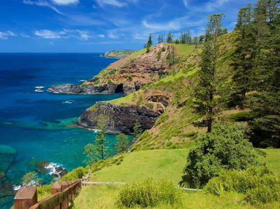 A pair of aged hands carefully touch a historical artifact (leg irons), captured in soft, diffused light, representing the emotional connection to the convict past.