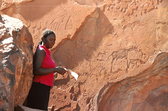 Topnaar elder preparing sand for baking guinea fowl, showcasing traditional culinary practices