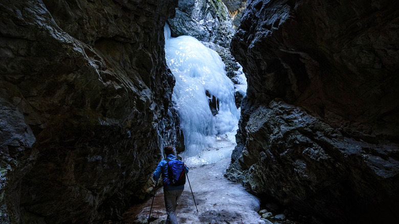 A canyoneer rappelling down a frozen waterfall in Switzerland, demonstrating the adrenaline-pumping experience and stunning winter scenery of winter canyoning.