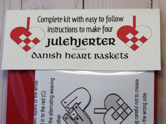 Close up of hands weaving red and white paper strips for a Julekurv.