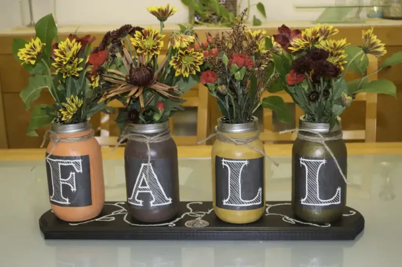A beautifully arranged fall centerpiece featuring pumpkins, gourds, and other autumnal elements on a dining table.