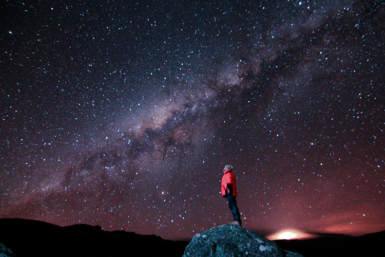 Javier sandboarding at sunset, a small figure against the immensity of the desert