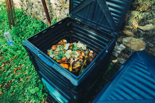 Woman turning compost in an outdoor bin