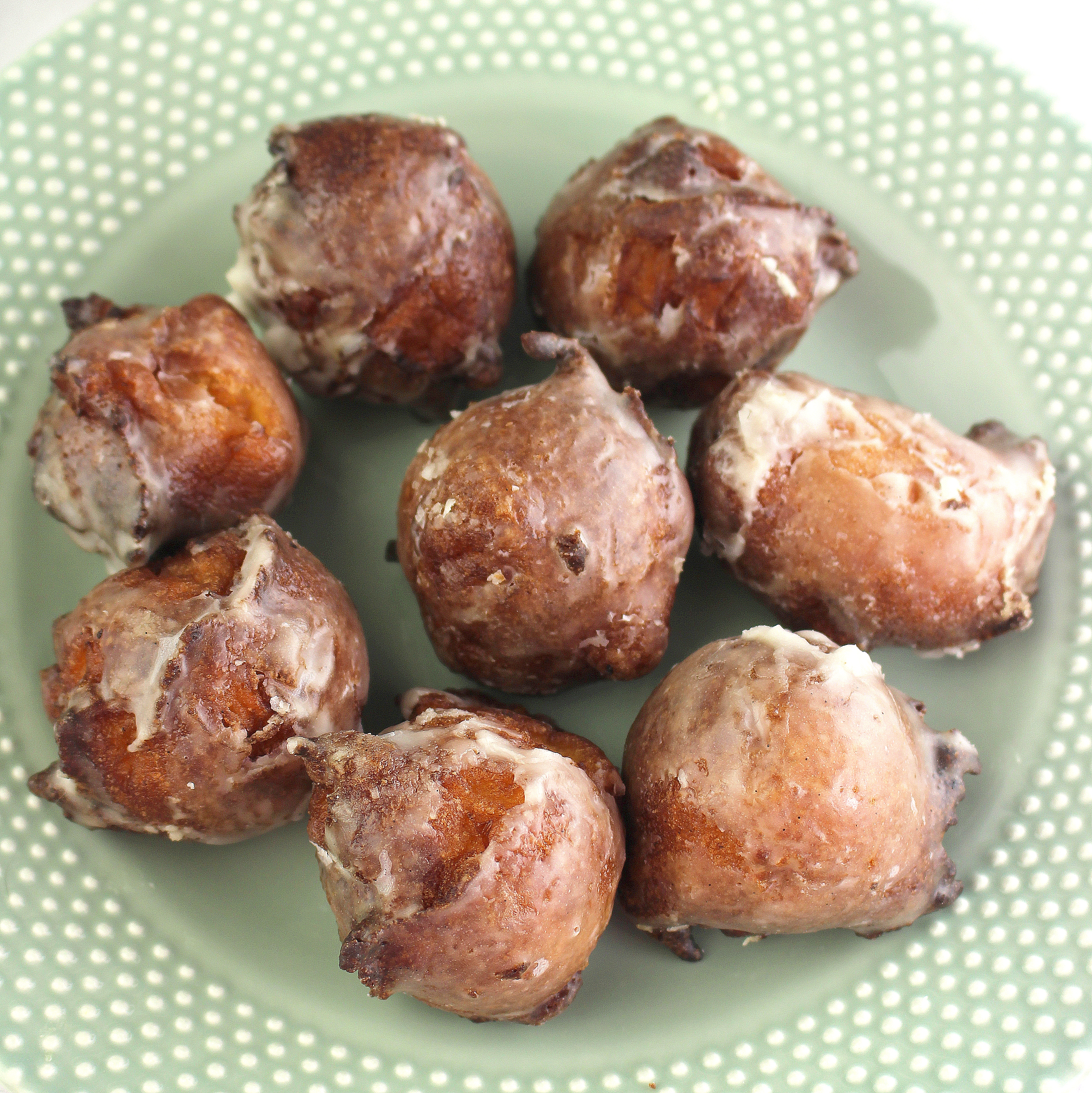 A stack of fritters on a rustic plate, drizzled with maple-walnut sauce, garnished with a sprinkle of walnuts