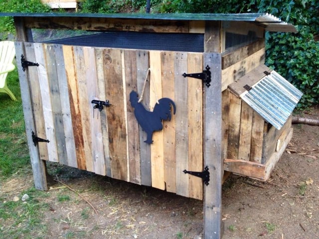 A partially constructed chicken coop with pallet walls being screwed together.