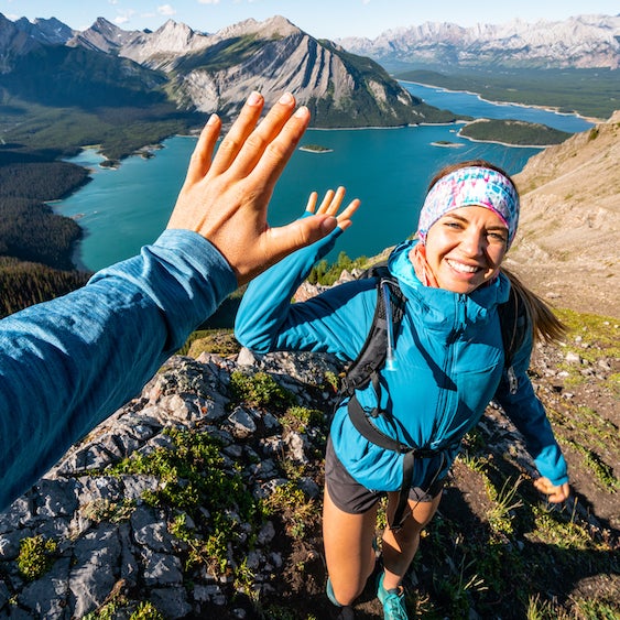 A family fat biking on a snowy trail alongside the Bow River in Banff National Park. The sun is shining, and the trees are covered in snow.