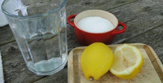 Close up of a person mixing baking soda and water to create a paste in a small rustic bowl. Natural light streams in from a nearby window, highlighting the texture of the ingredients