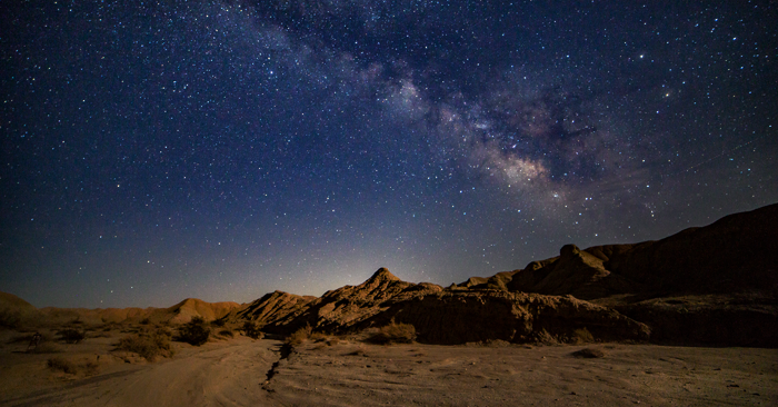 A breathtaking view of the Milky Way arching over the Atacama Desert, with the ALMA telescopes visible in the foreground, highlighting the clear, dark skies perfect for astrophotography.