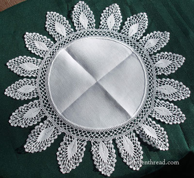 Close-up of a linen doily featuring a detailed crochet border, highlighting the texture and craftsmanship.