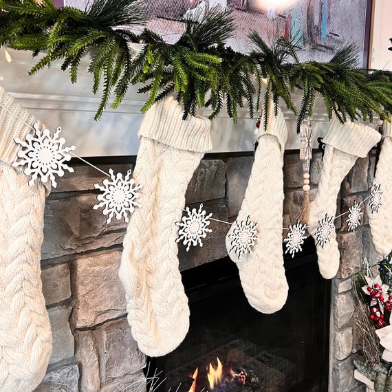DIY white paper snowflake garland draped across a Scandinavian fireplace mantel, adding a delicate and whimsical touch to the decor.