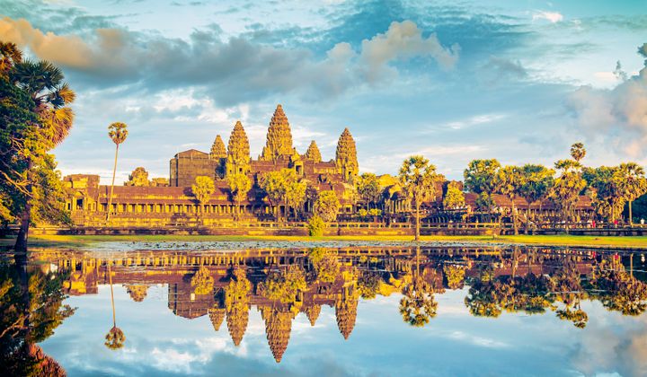 Angkor Wat reflecting in the moat at sunrise, showcasing the golden light and silhouette of the temple