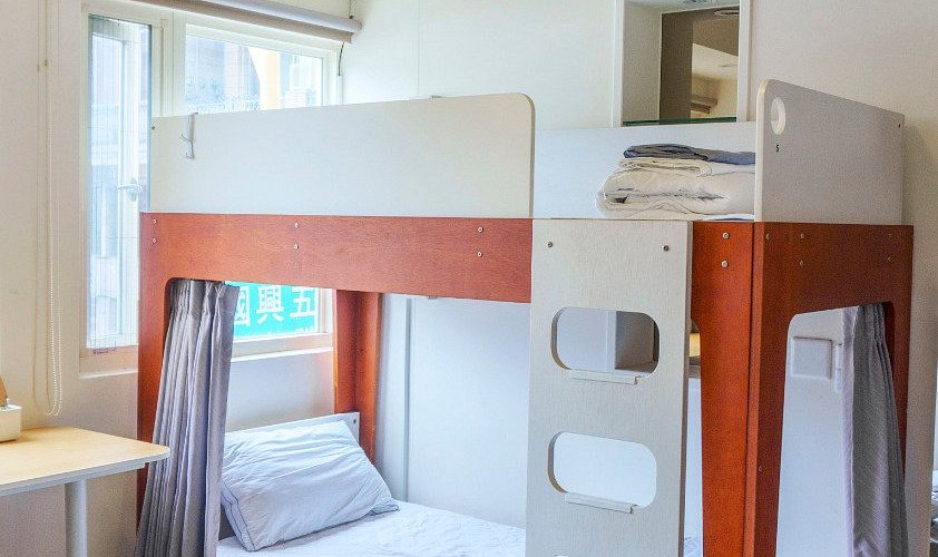 A cozy hostel dorm room with bunk beds, privacy curtains, and individual reading lights