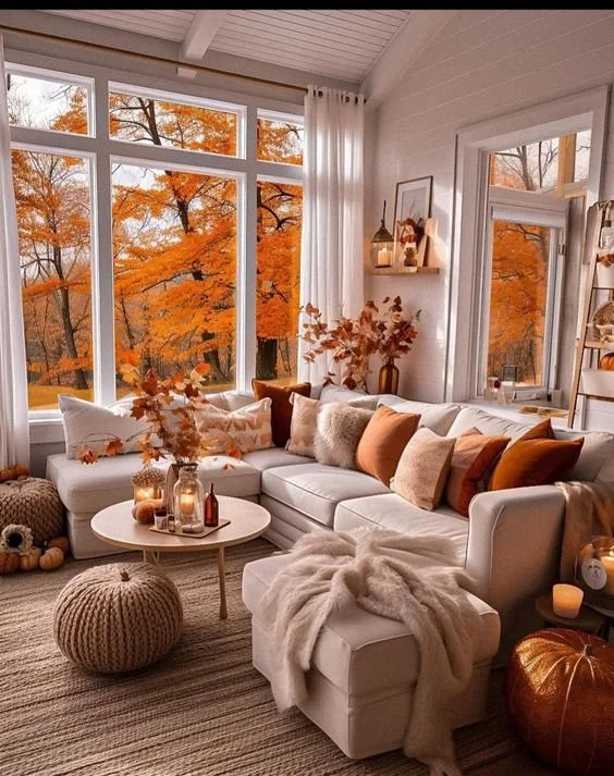 A close-up shot showcases a farmhouse living room mantel adorned with pumpkins, gourds, corn stalks, candles, and string lights, creating a warm and inviting autumn display.