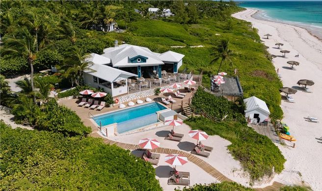 A couple silhouetted against a vibrant sunset during a couples yoga session on Radhanagar Beach, with the turquoise sea in the background.