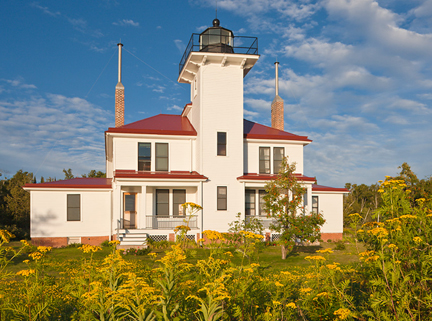 Apostle Islands Lighthouse on a rocky island, with a clear blue sky and Lake Superior surrounding it