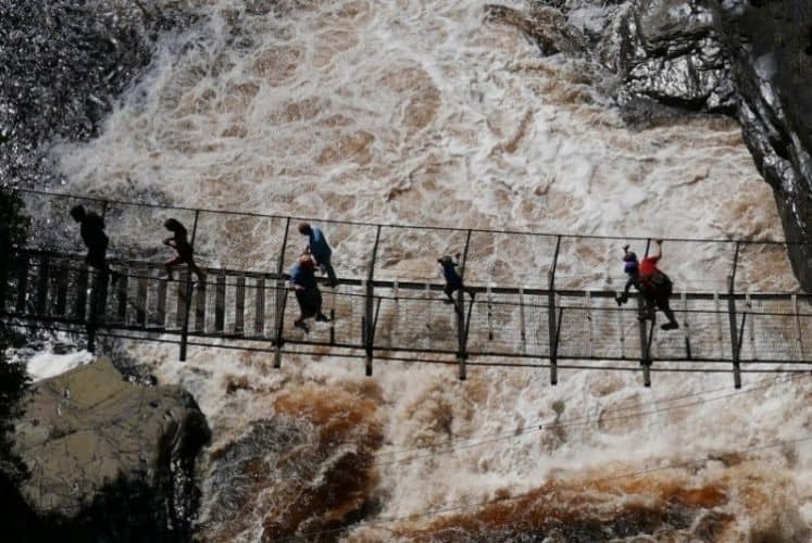 A lone climber on the via ferrata at Canyon Sainte-Anne, showcasing the icy rock face and the breathtaking view of the canyon below.