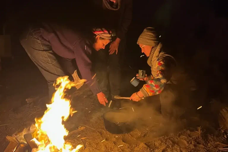 A person taking stew off of a campfire