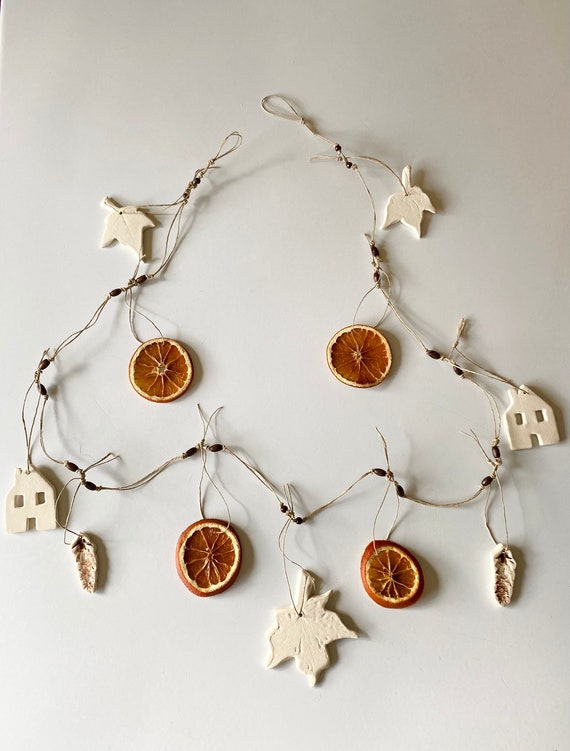 Detail shot of a dried orange garland cascading from the top of an antique hutch, highlighting the intricate details and textures of the dried citrus.