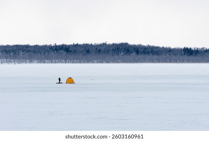 A wide shot of ice fishing tents on Lake Shikaribetsu, showcasing the vastness of the frozen landscape. The colorful tents dot the white expanse of the lake, creating a picturesque winter scene.