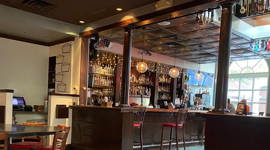 A sunlit hotel room with sheer curtains, vintage furniture, and an oriental rug, evoking a sense of nostalgia and history.