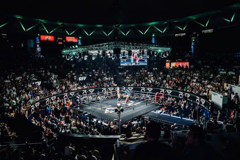 A close-up photo of a bowl of Kuay Teow Reua (boat noodles) with dark broth, rice noodles, and various toppings, representing a unique culinary experience in Bangkok