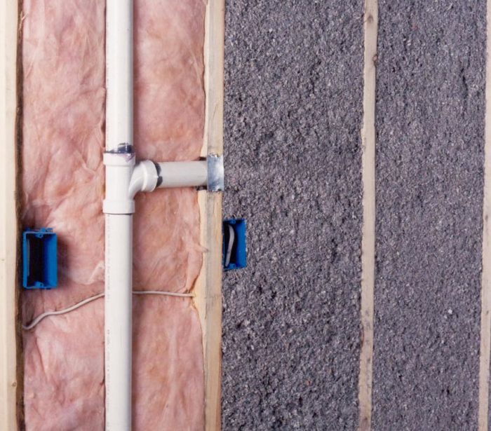 Worker blowing cellulose insulation into a wall cavity.