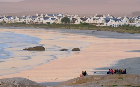 A plate of sustainably caught seafood beautifully presented in a restaurant overlooking the ocean in Paternoster. Golden hour lighting, highlighting the textures and colors of the food. The seafood is the central focus, with the ocean view adding to the ambiance.