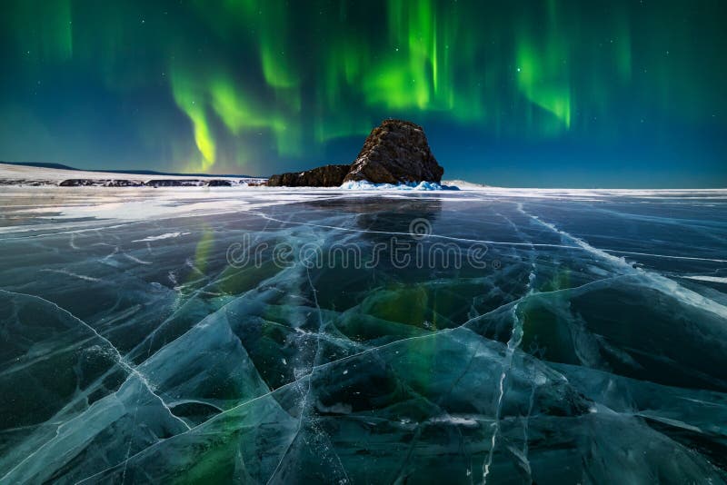 A panoramic view of Lake Baikal stretching to the horizon with ice sailers in the distance.