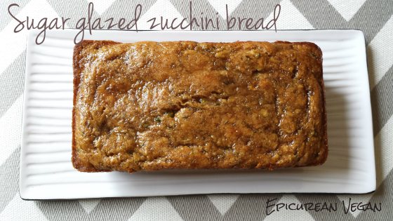 Freshly baked zucchini bread with honey-lavender glaze on a wooden cutting board. The bread is sliced, and the glaze glistens in the sunlight.