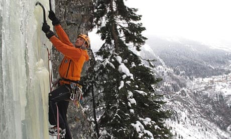 An ice climber ascending a glistening blue ice waterfall in the Bernese Oberland.