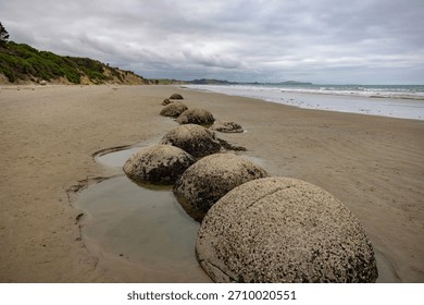 Moeraki Boulders scattered along the beach, highlighting their spherical shape and varying sizes