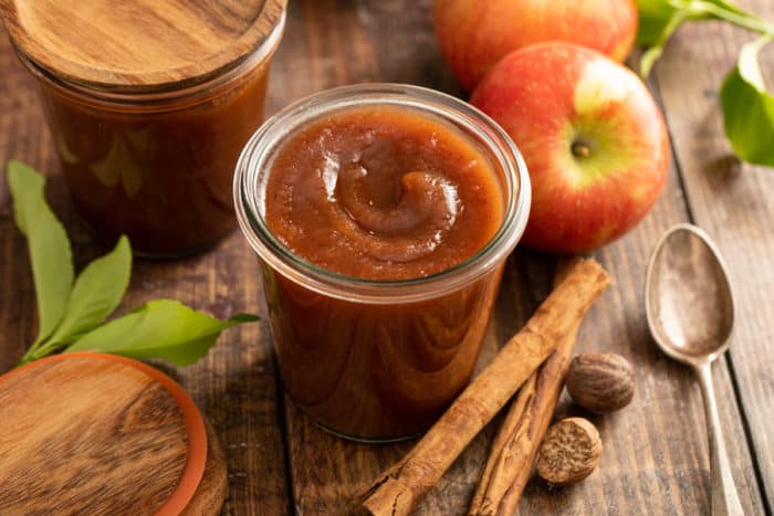 Ingredients for apple butter arranged on a wooden table, featuring apples, spices, brown sugar, and apple cider, emphasizing fresh and local produce