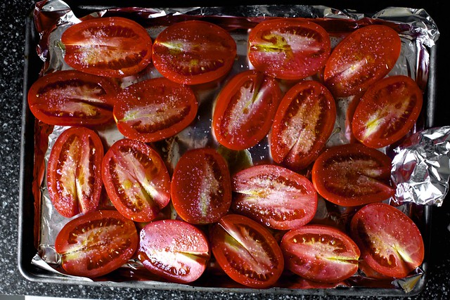 Overhead shot of sliced tomatoes, bread, basil, and other ingredients on a rustic wooden surface, ready for making bruschetta