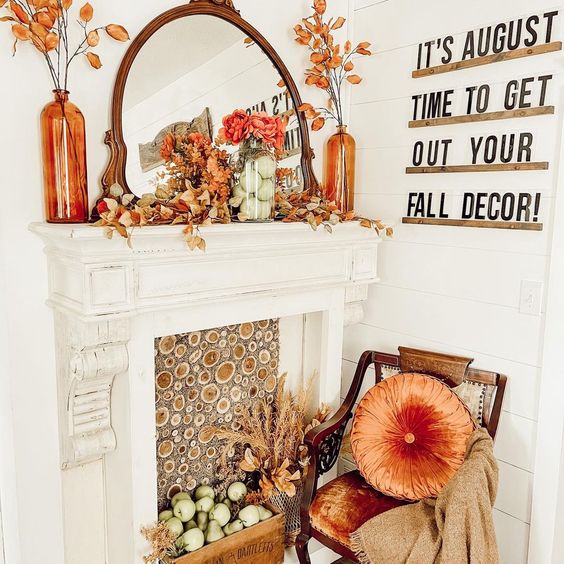 A collection of antique brass candlesticks on a mantel, surrounded by pumpkins and foliage, illustrating the use of thrifted vintage pieces in fall decor.