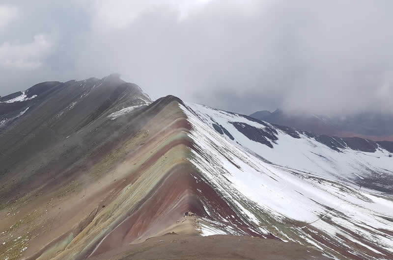 A close-up shot of the colorful striations of Rainbow Mountain, highlighting the different mineral layers.