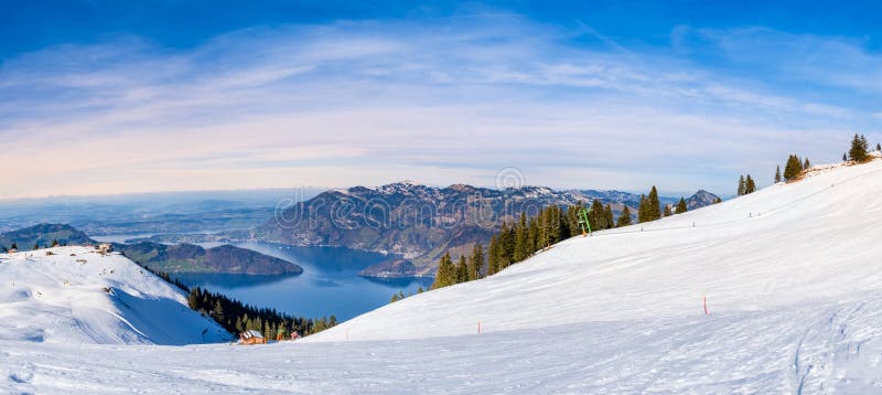A skier carves down a pristine, snow-covered mountain slope in the Swiss Alps, showcasing the exhilaration and freedom of downhill skiing with stunning panoramic views.